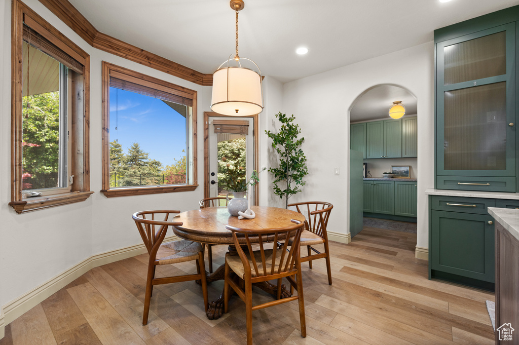 Dining room featuring light wood-style floors, baseboards, recessed lighting, and arched walkways