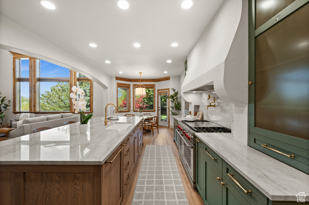 Kitchen featuring a sink, green cabinets, light wood-style flooring, range with two ovens, and recessed lighting