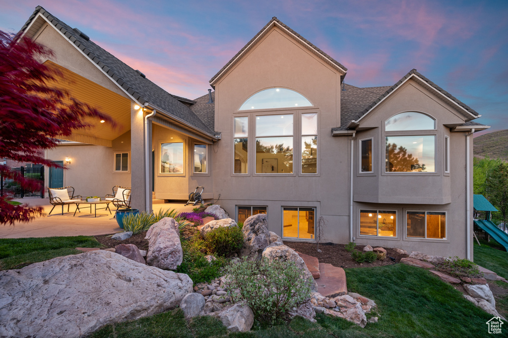 Back of house featuring a patio area, stucco siding, and a lawn