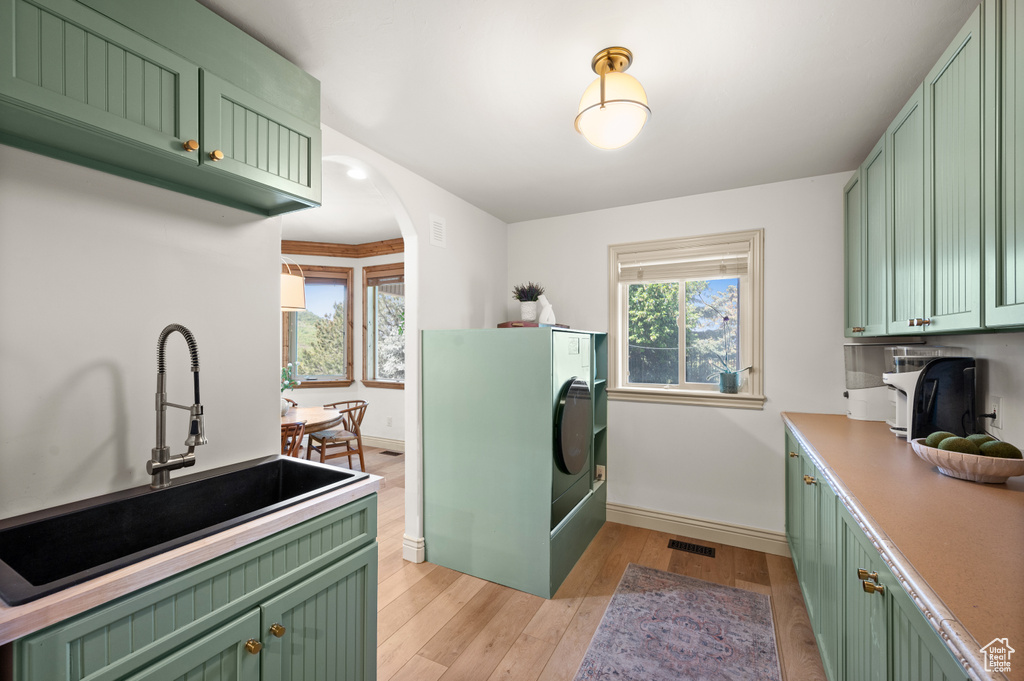 Clothes washing area featuring baseboards, light wood-type flooring, arched walkways, and washer / clothes dryer