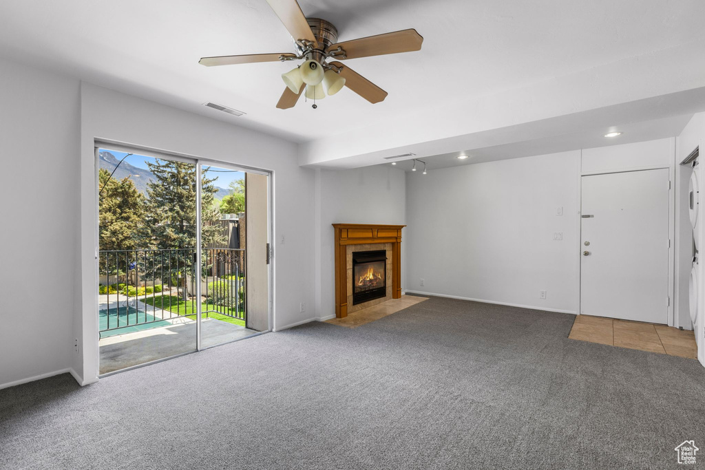 Unfurnished living room with carpet flooring, ceiling fan, a fireplace, and baseboards