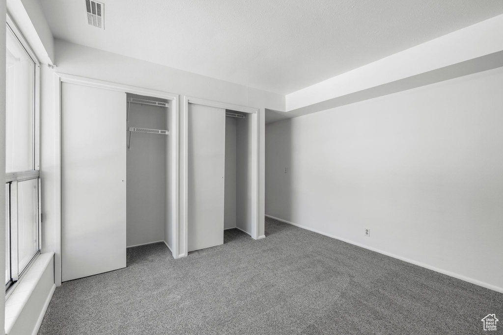 Unfurnished bedroom with carpet flooring and multiple closets