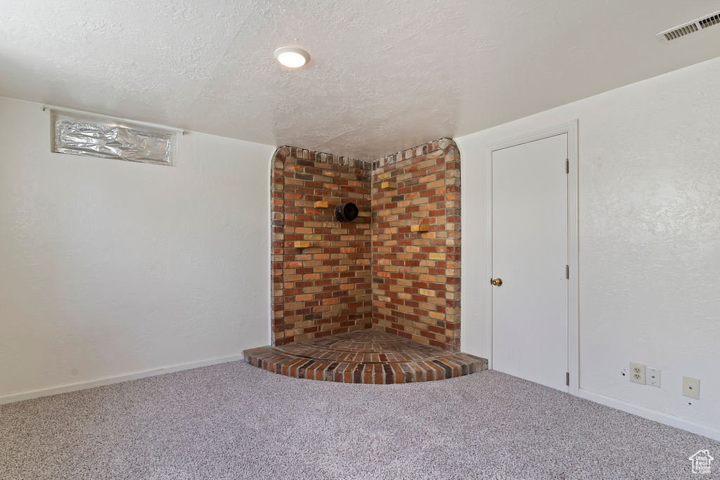 Unfurnished living room with a textured ceiling, carpet flooring, and baseboards