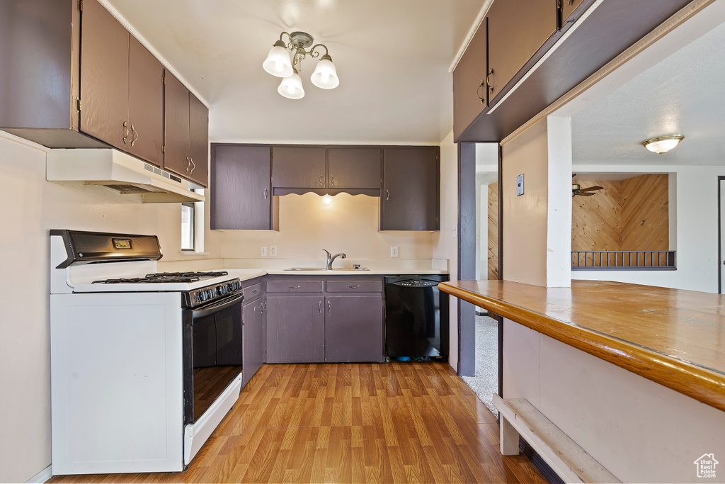 Kitchen featuring white gas range oven, dishwasher, a sink, light wood finished floors, and under cabinet range hood