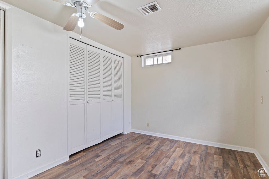 Unfurnished bedroom with wood finished floors, a closet, baseboards, and ceiling fan