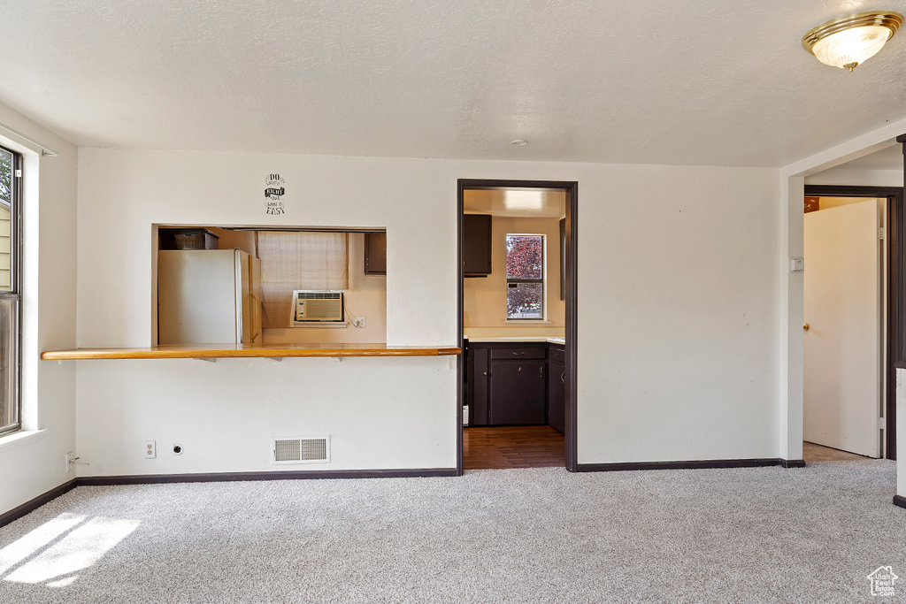 Empty room featuring carpet flooring, baseboards, and a wall mounted air conditioner