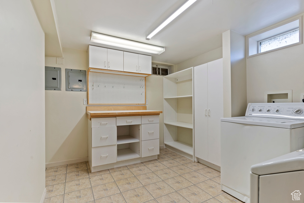 Clothes washing area with washer / clothes dryer, electric panel, baseboards, and light tile patterned floors