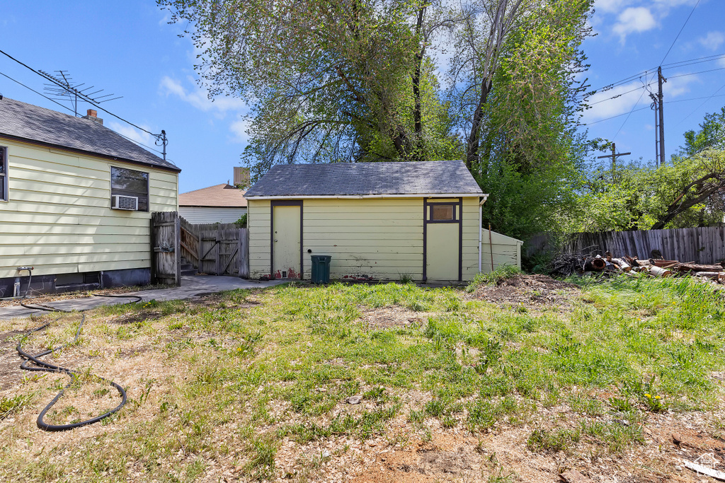 Fenced backyard with an outbuilding, a shed, and cooling unit