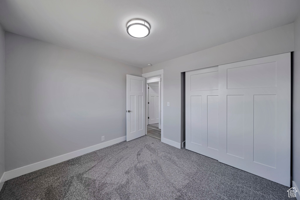 Unfurnished bedroom featuring carpet, baseboards, and a closet