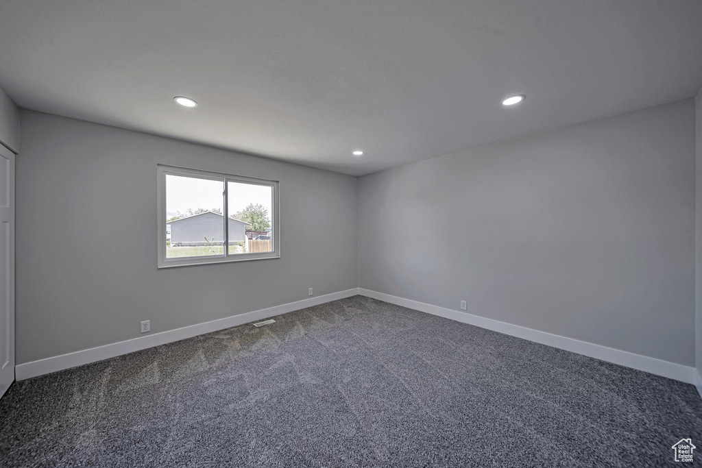 Unfurnished room with dark colored carpet, baseboards, and recessed lighting