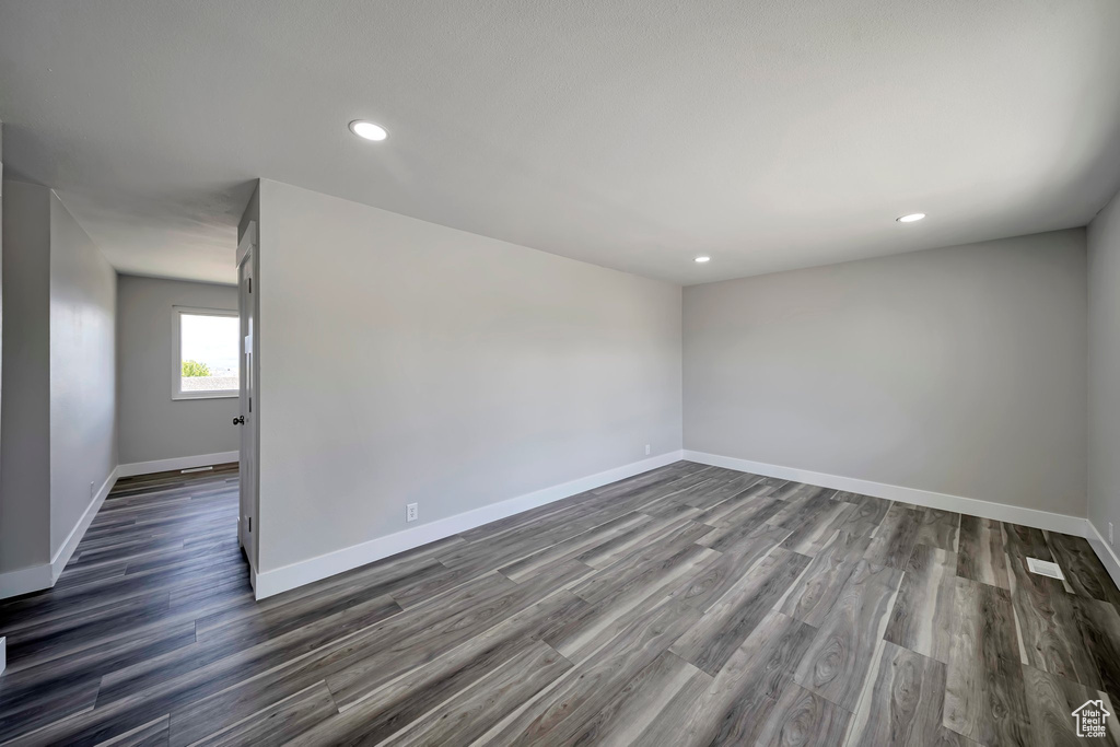 Spare room featuring baseboards, dark wood-type flooring, and recessed lighting
