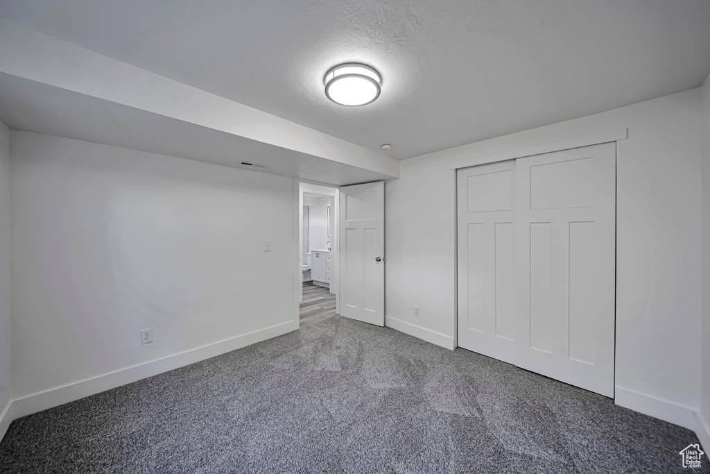 Unfurnished bedroom with baseboards, carpet floors, a textured ceiling, and a closet