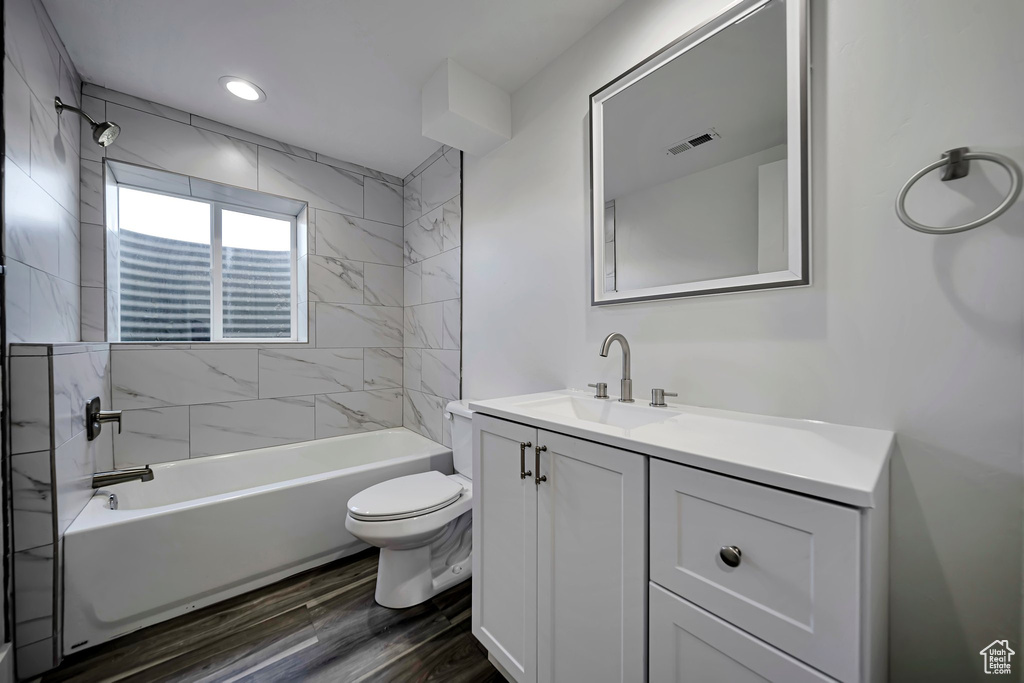 Bathroom with toilet, vanity, wood finished floors, and bathing tub / shower combination