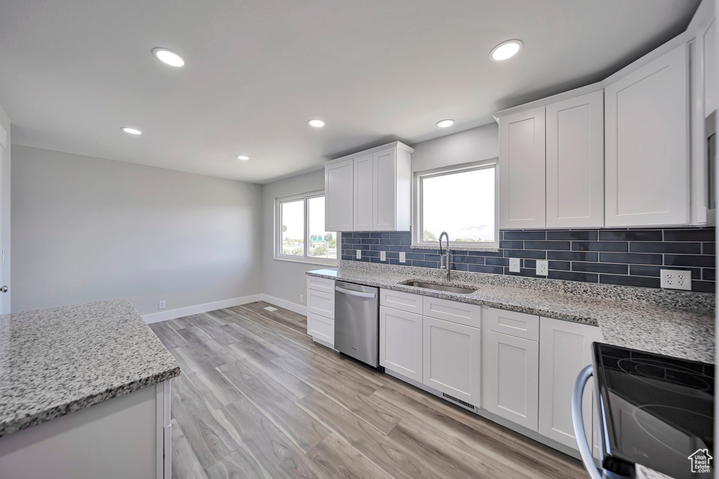 Kitchen with a sink, dishwasher, range with electric cooktop, tasteful backsplash, and baseboards