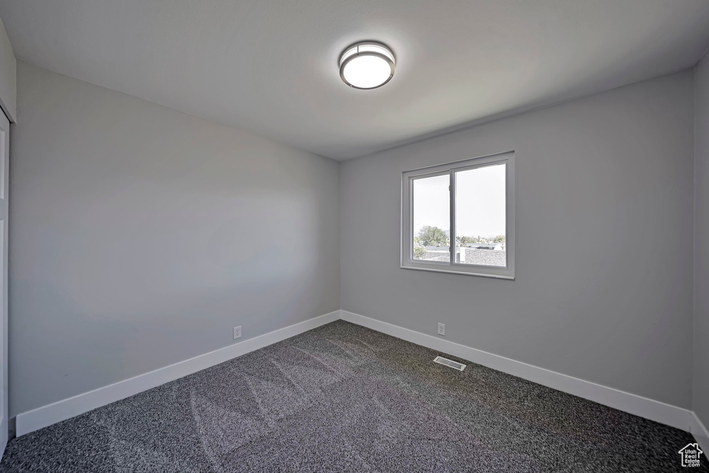 Spare room featuring baseboards and dark carpet
