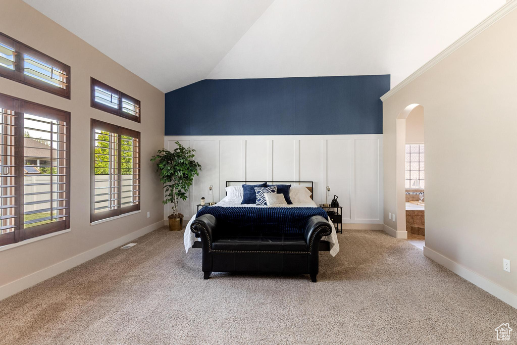 Bedroom with high vaulted ceiling, arched walkways, and carpet