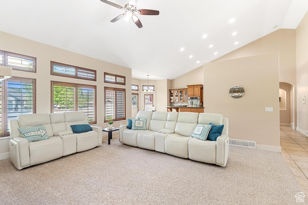 Living room with high vaulted ceiling, arched walkways, ceiling fan, light carpet, and baseboards