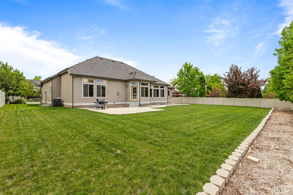 Back of house with a patio area, central AC unit, stucco siding, and roof with shingles