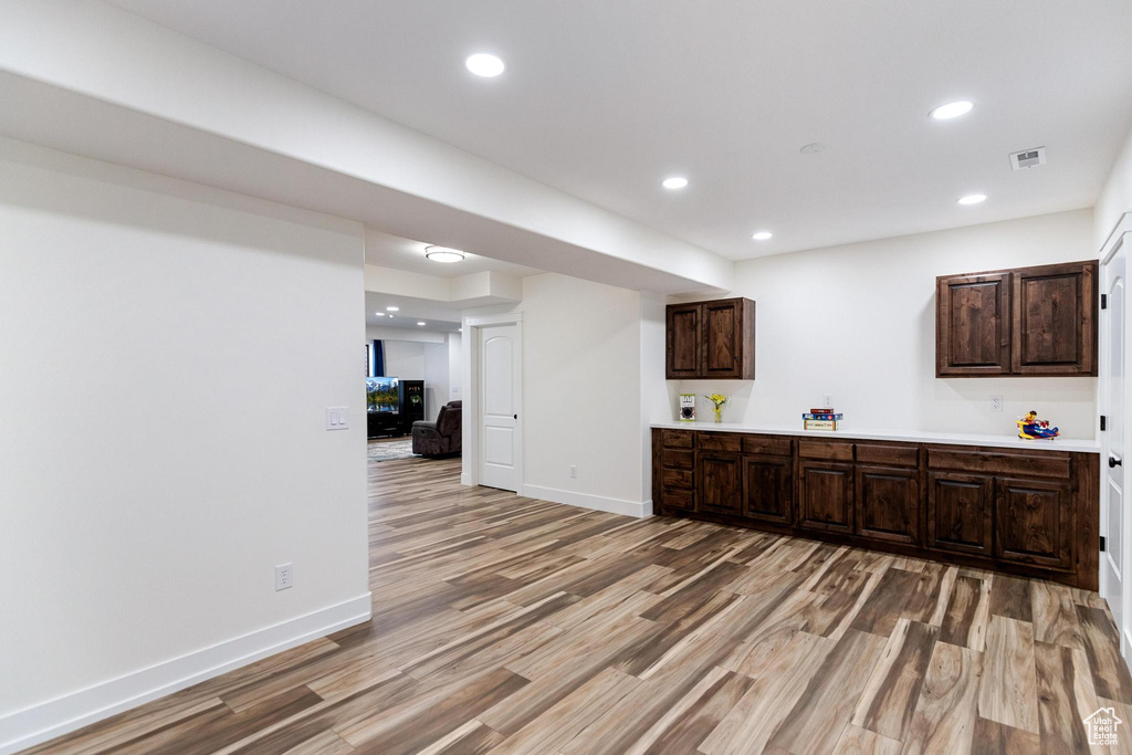 Kitchen with light wood-type flooring, light countertops, dark brown cabinets, recessed lighting, and baseboards