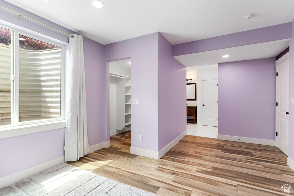 Unfurnished bedroom with multiple windows, baseboards, light wood finished floors, recessed lighting, and a closet