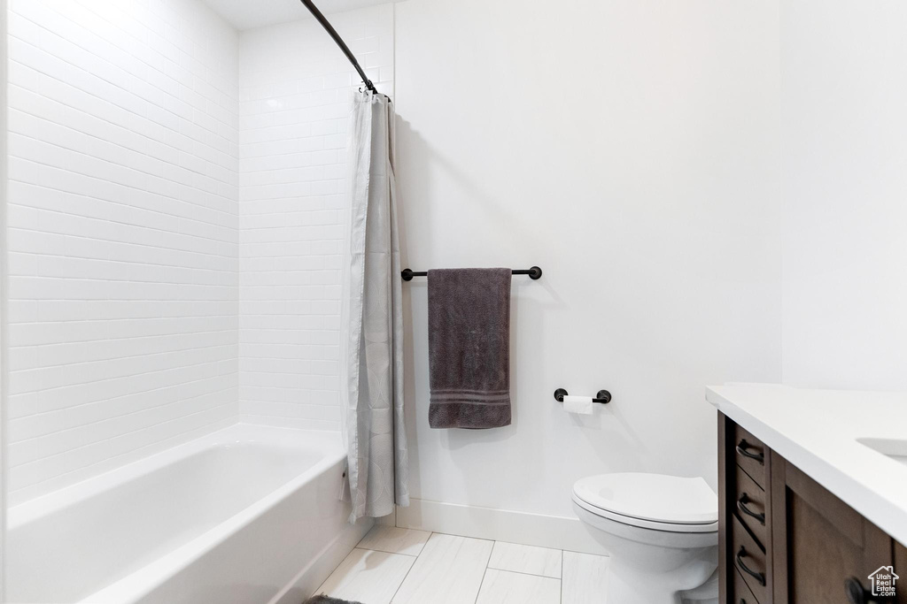 Bathroom featuring tile patterned floors, toilet, vanity, baseboards, and shower / bath combo with shower curtain