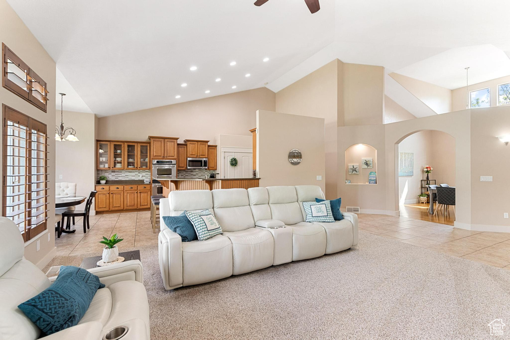 Living area with light tile patterned floors, arched walkways, high vaulted ceiling, ceiling fan, and recessed lighting