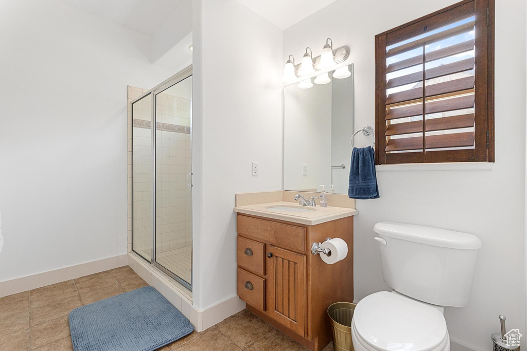 Bathroom featuring a shower stall, vanity, toilet, baseboards, and tile patterned flooring
