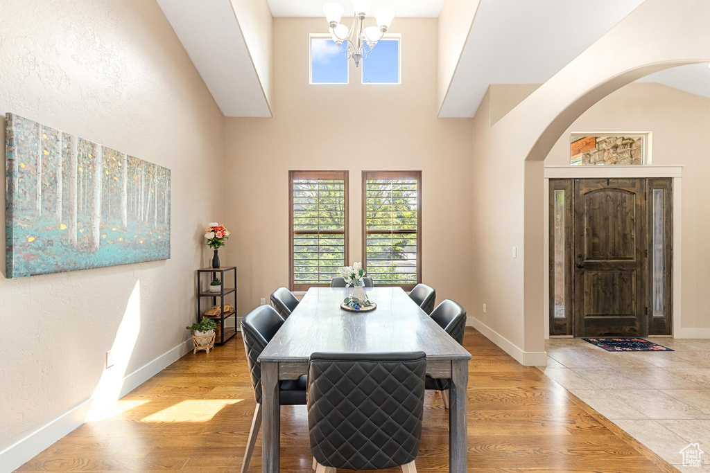 Dining space with arched walkways, a chandelier, baseboards, and light wood-style flooring