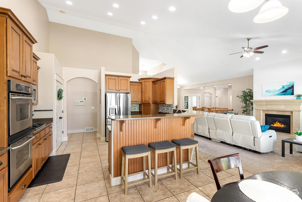 Kitchen with stainless steel appliances, a kitchen breakfast bar, open floor plan, ceiling fan, and light tile patterned flooring