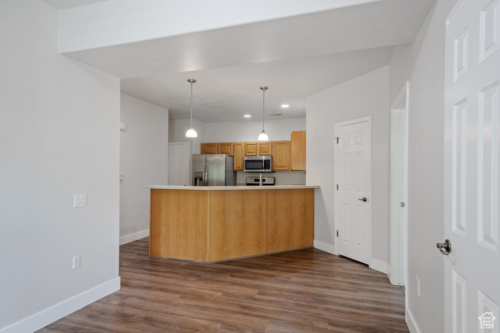 Kitchen featuring stainless steel appliances, baseboards, a peninsula, dark wood-style floors, and recessed lighting