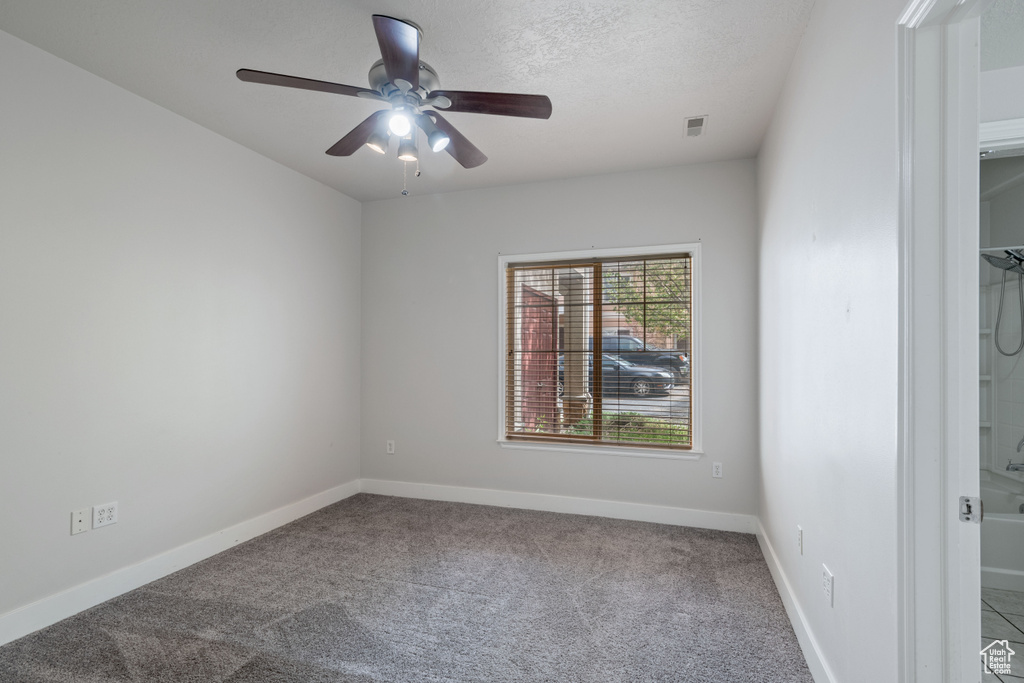 Carpeted spare room with ceiling fan and baseboards