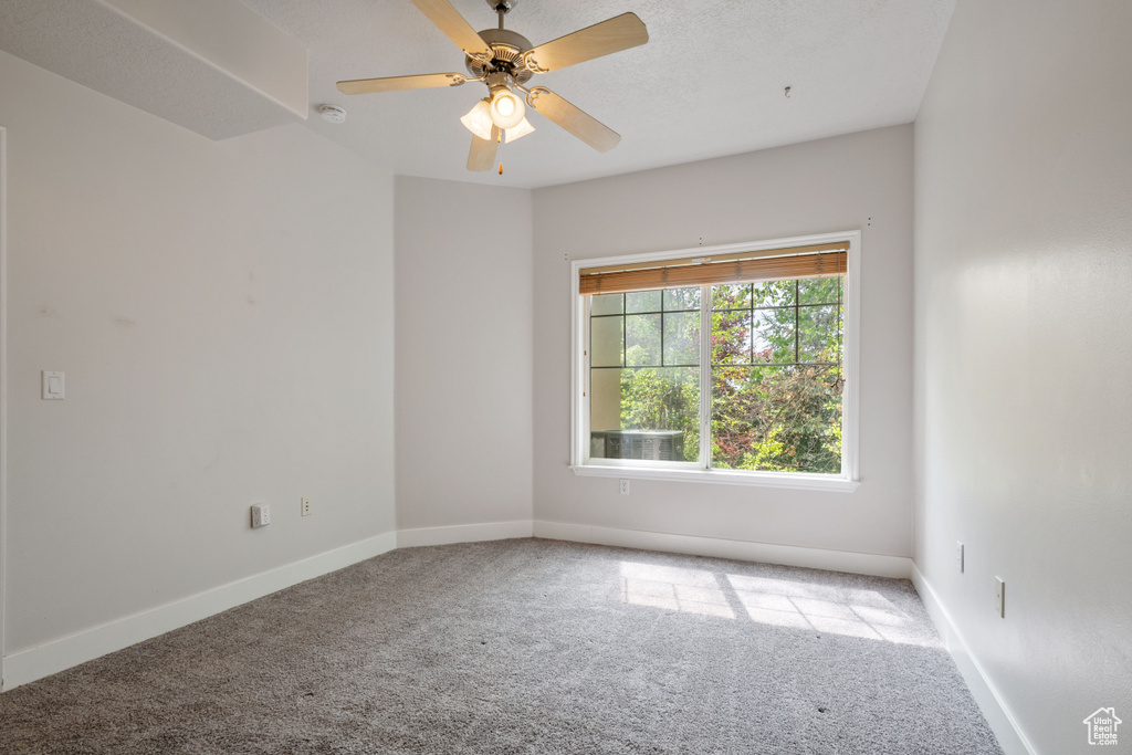 Carpeted spare room featuring baseboards, a ceiling fan, and a smoke detector