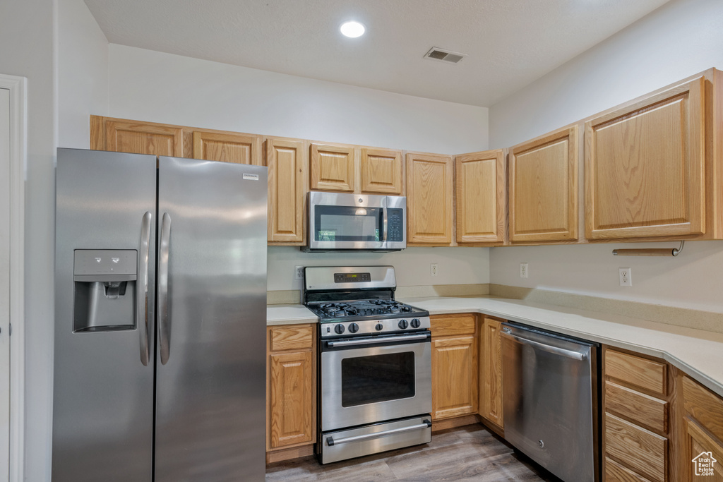 Kitchen featuring appliances with stainless steel finishes, dark wood-style floors, light countertops, and light brown cabinetry