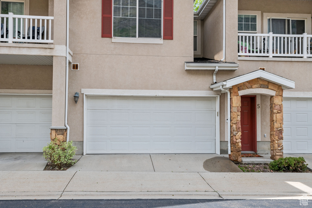 View of front facade featuring an attached garage, stone siding, stucco siding, and driveway