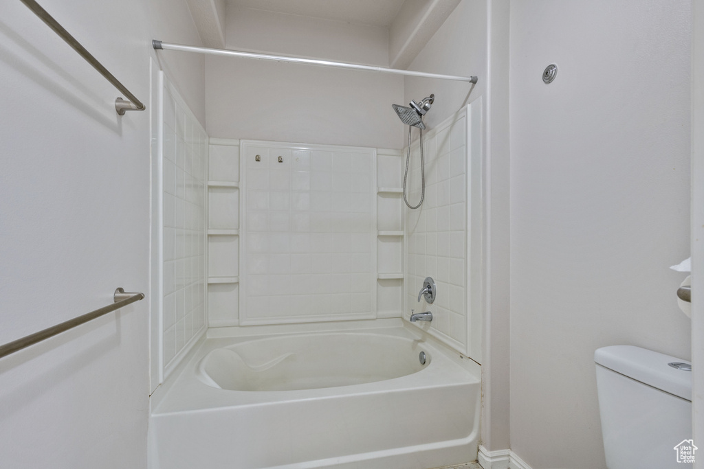 Full bathroom featuring toilet, baseboards, and  shower combination