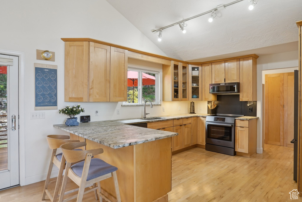Kitchen with stainless steel electric range, a sink, vaulted ceiling, a peninsula, and track lighting