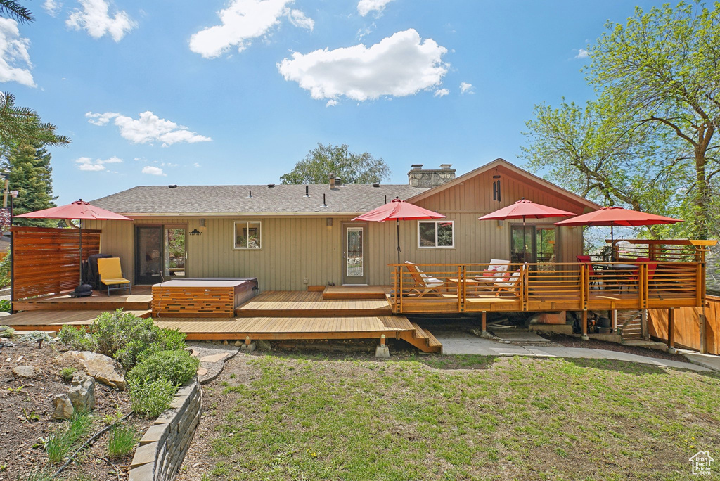 Back of house with a wooden deck, a lawn, a chimney, and roof with shingles