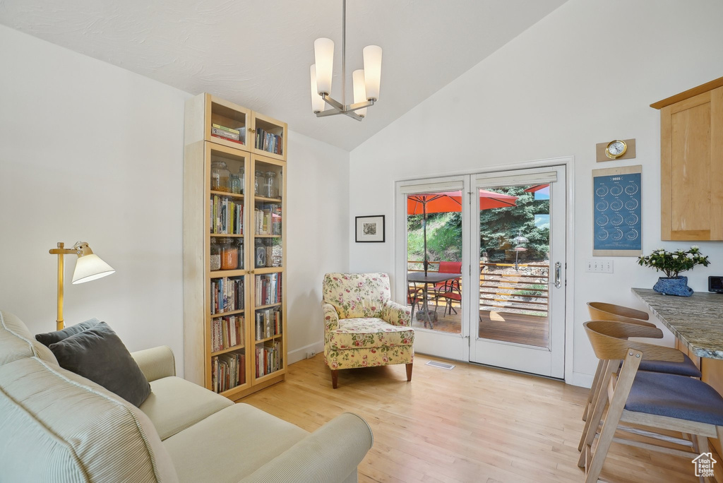 Sitting room with a chandelier, light wood-style floors, and high vaulted ceiling