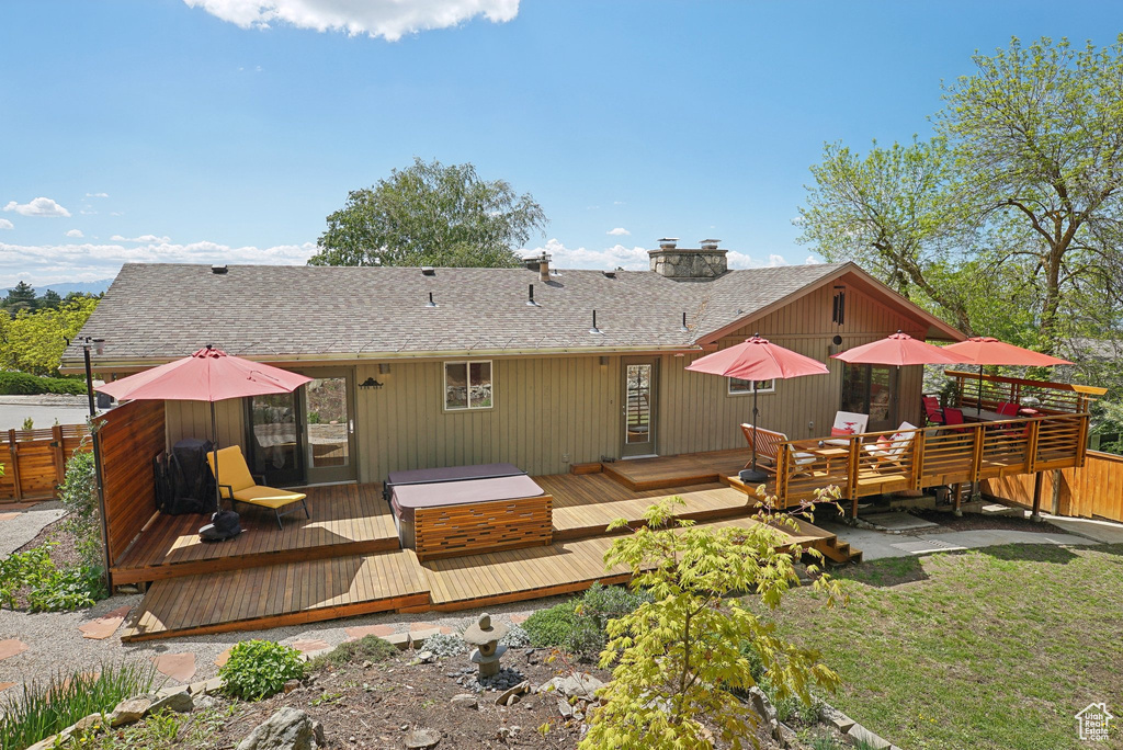 Rear view of house featuring a shingled roof, a wooden deck, and fence