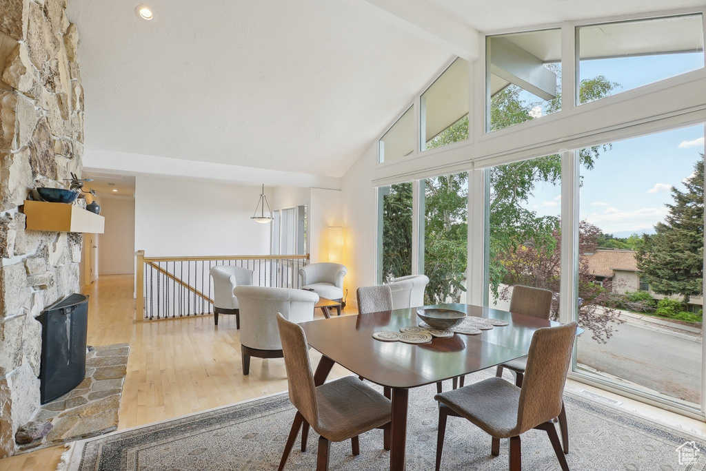 Dining area featuring wood-type flooring, high vaulted ceiling, and beamed ceiling