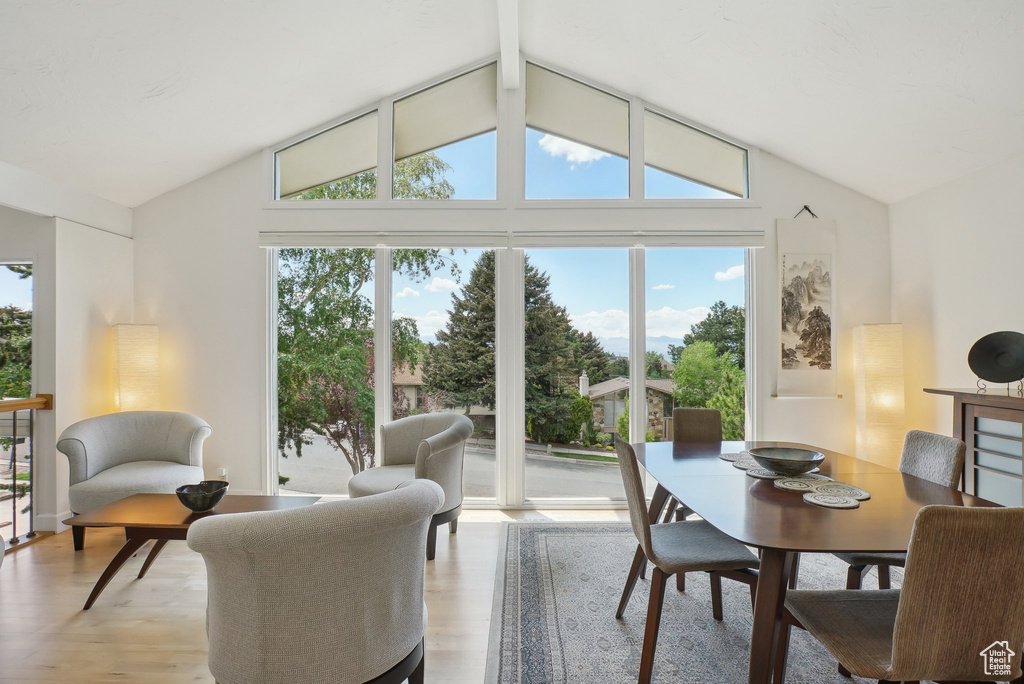 Dining room with vaulted ceiling, light wood-type flooring, and healthy amount of natural light