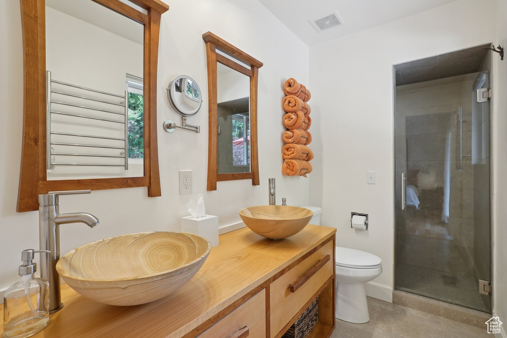 Full bathroom featuring a shower stall, toilet, vanity, and tile patterned flooring