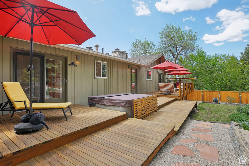Wooden deck with a covered hot tub and fence