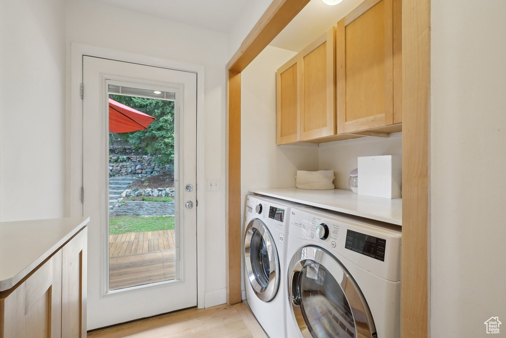 Laundry area featuring cabinet space, washer and clothes dryer, and light wood-type flooring
