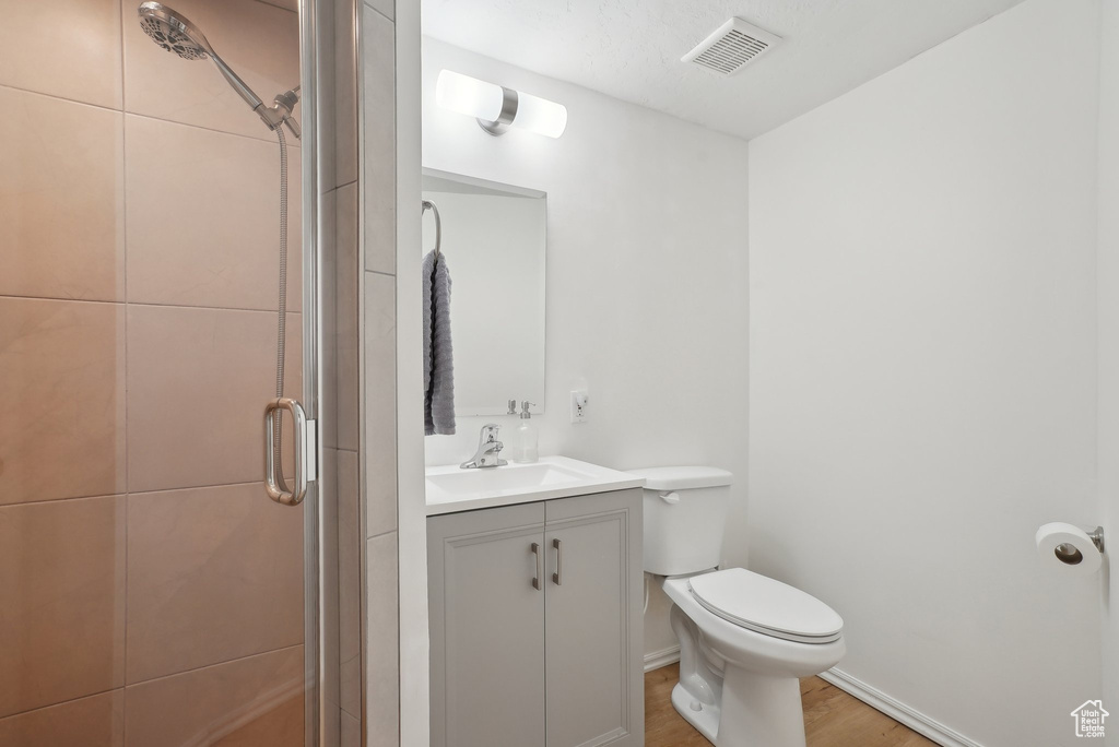 Bathroom with a stall shower, toilet, vanity, and wood finished floors
