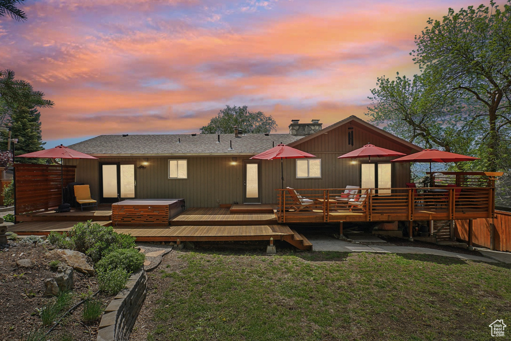 Rear view of property with a deck, a lawn, and a chimney