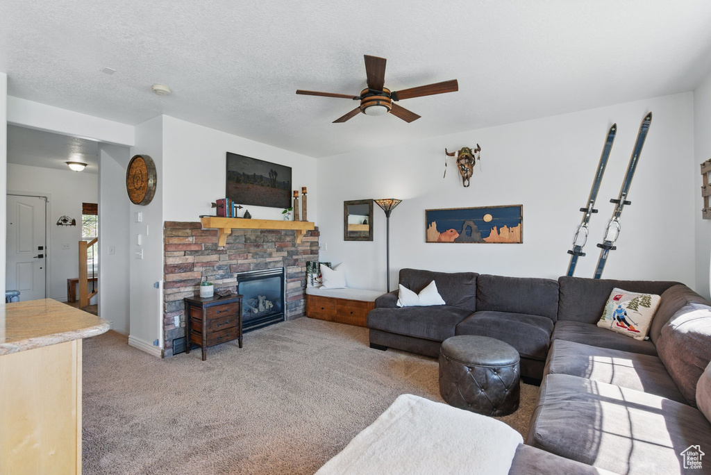 Living room with a ceiling fan, light carpet, and a stone fireplace