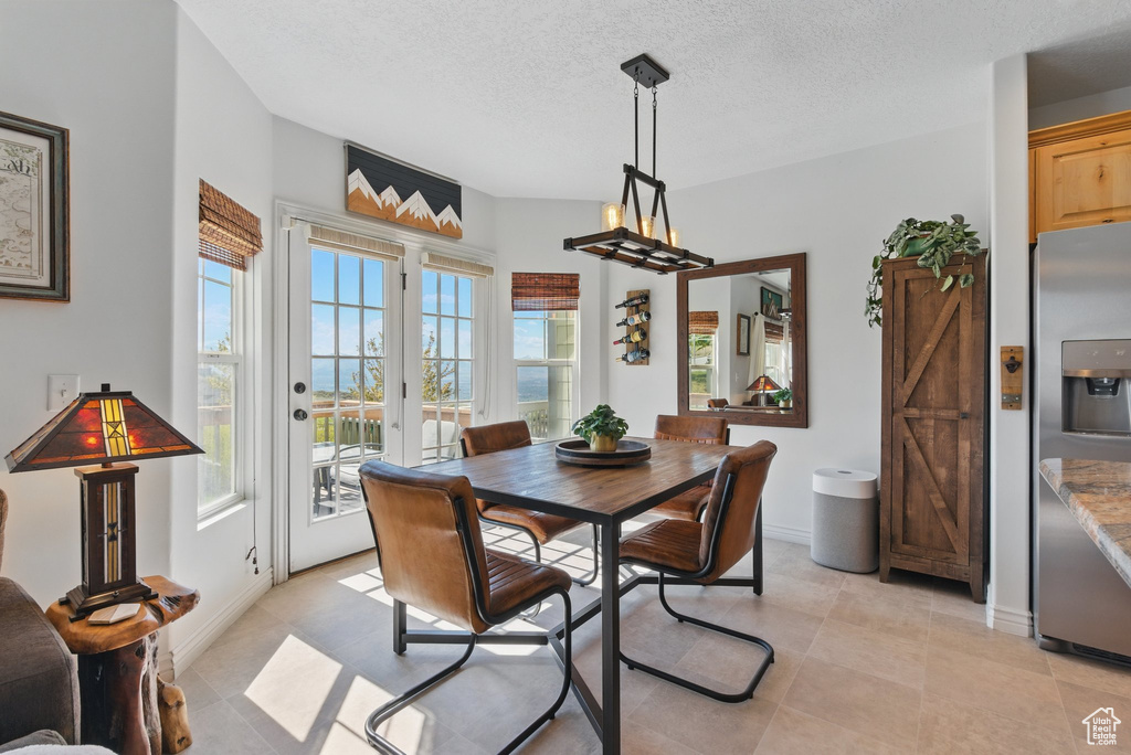 Dining area featuring a textured ceiling, light tile patterned flooring, and baseboards