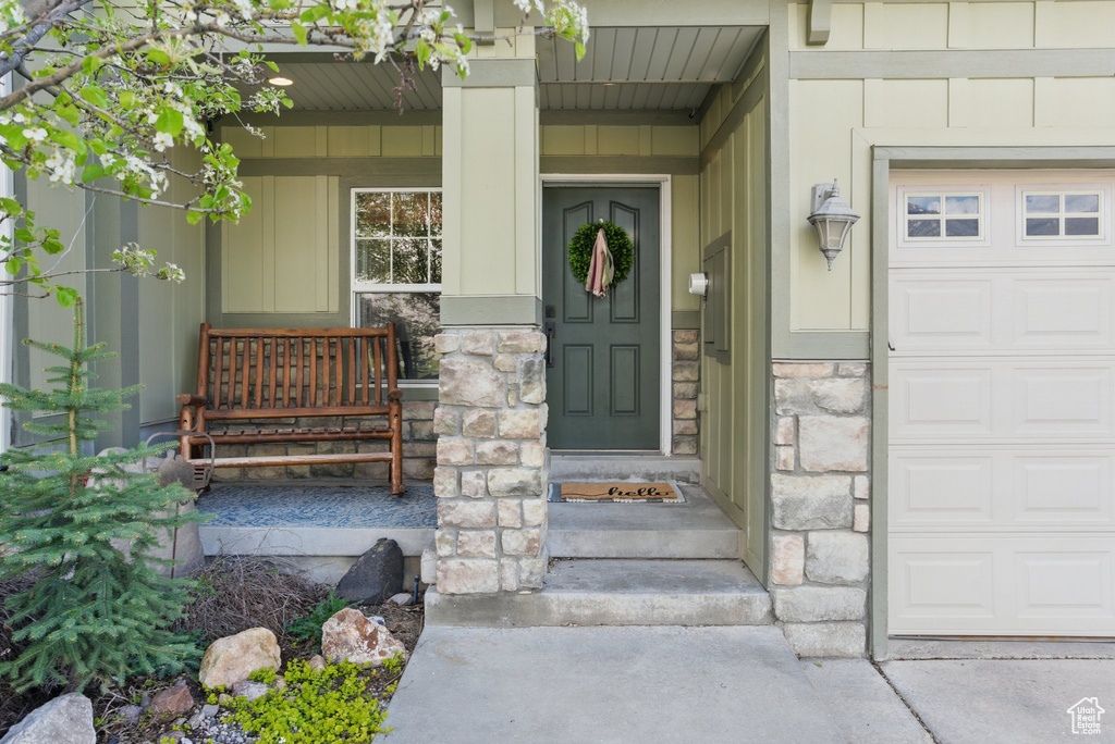 Entrance to property featuring a garage, stone siding, and a porch