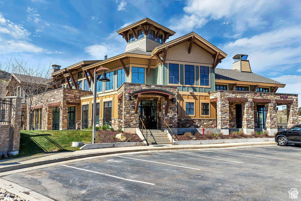 View of front of property featuring stone siding, a chimney, and uncovered parking